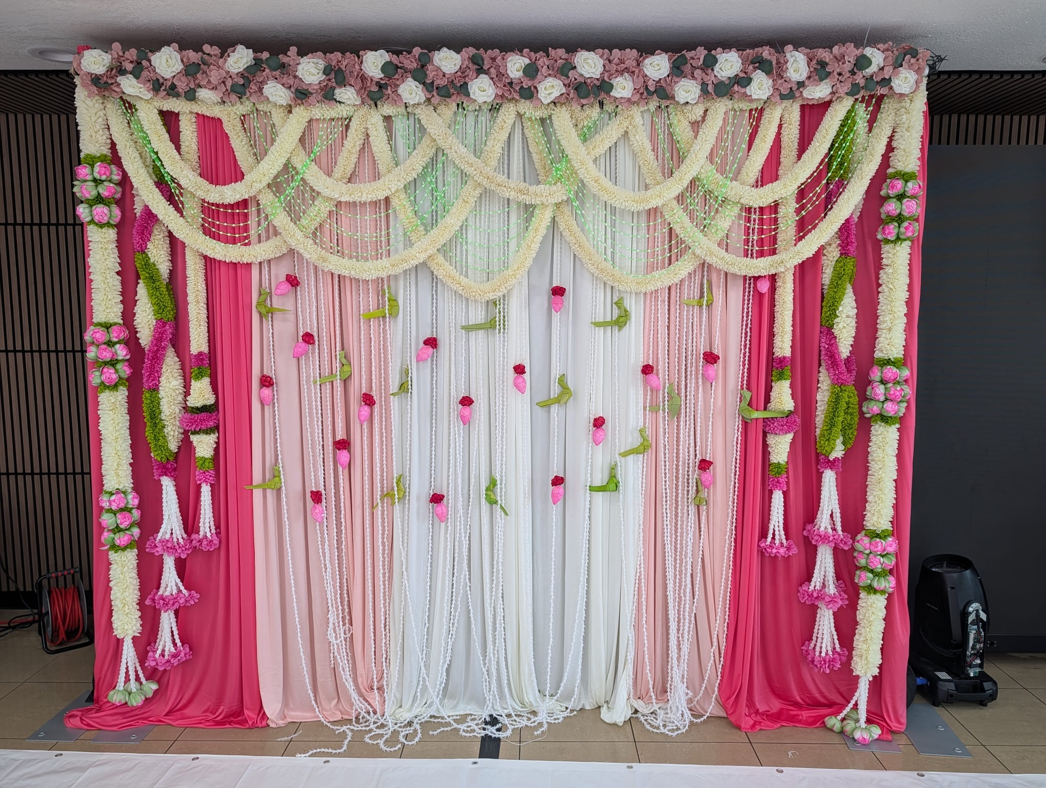 Pink and white floral backdrop with hanging garlands and draped panels