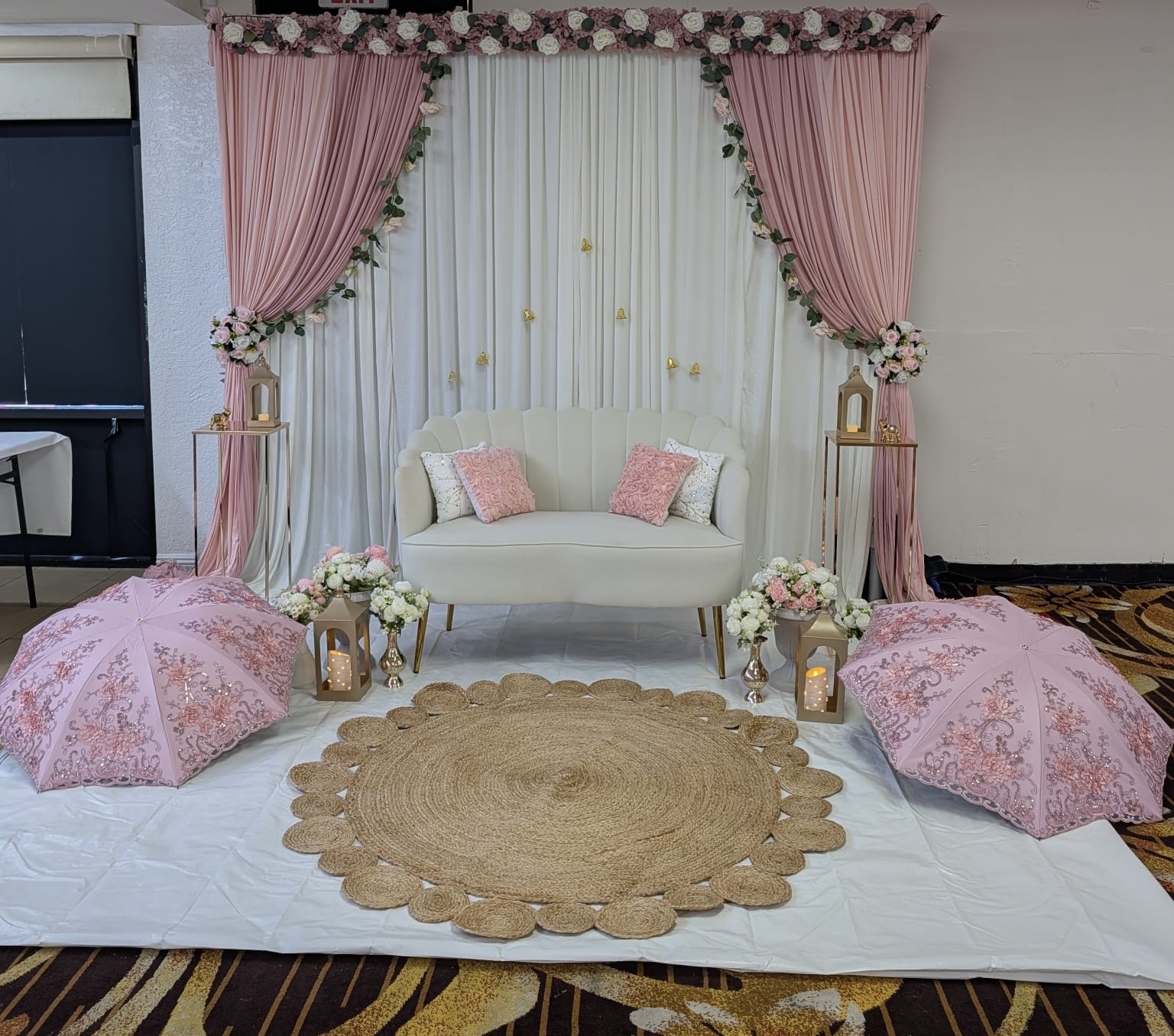 Pink and white lounge backdrop with floral draping and decorative umbrellas
