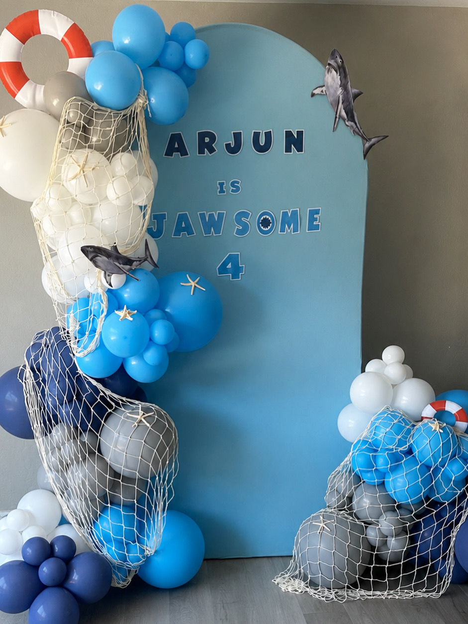 Shark themed fourth birthday backdrop with blue balloon decor