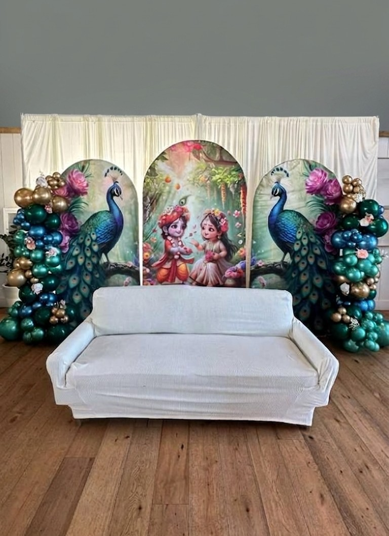 Peacock-themed celebration backdrop with Krishna and Radha artwork
