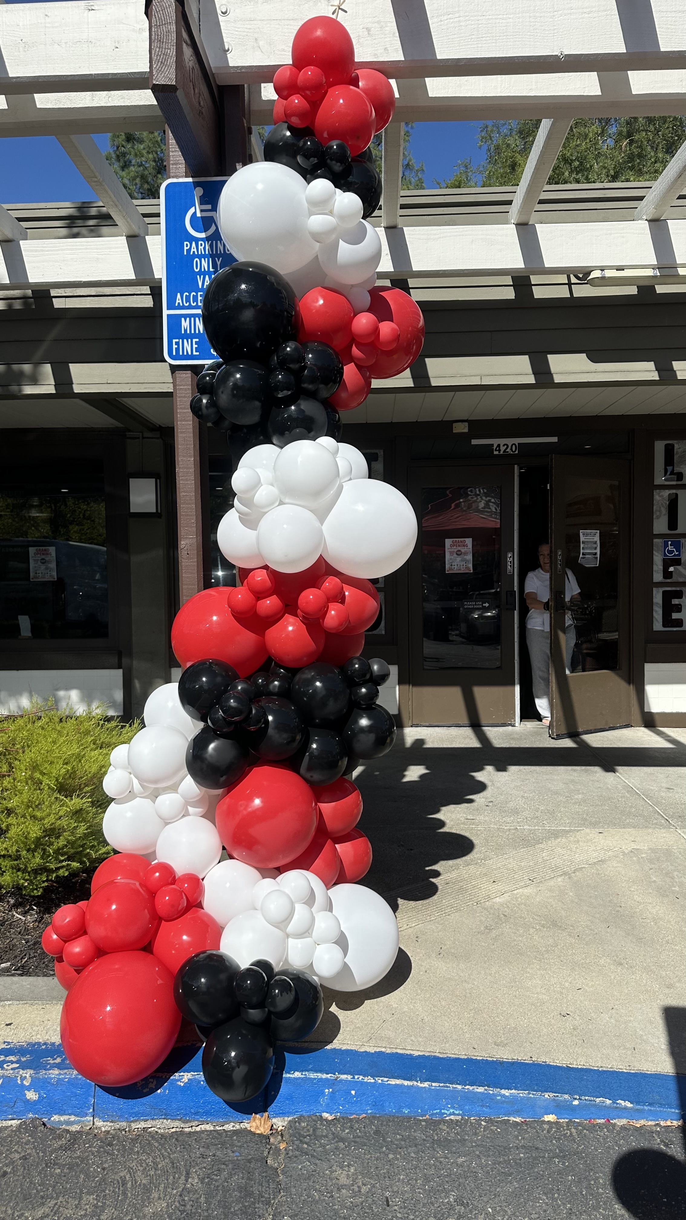 Grand opening storefront with red, white, and black balloon decor